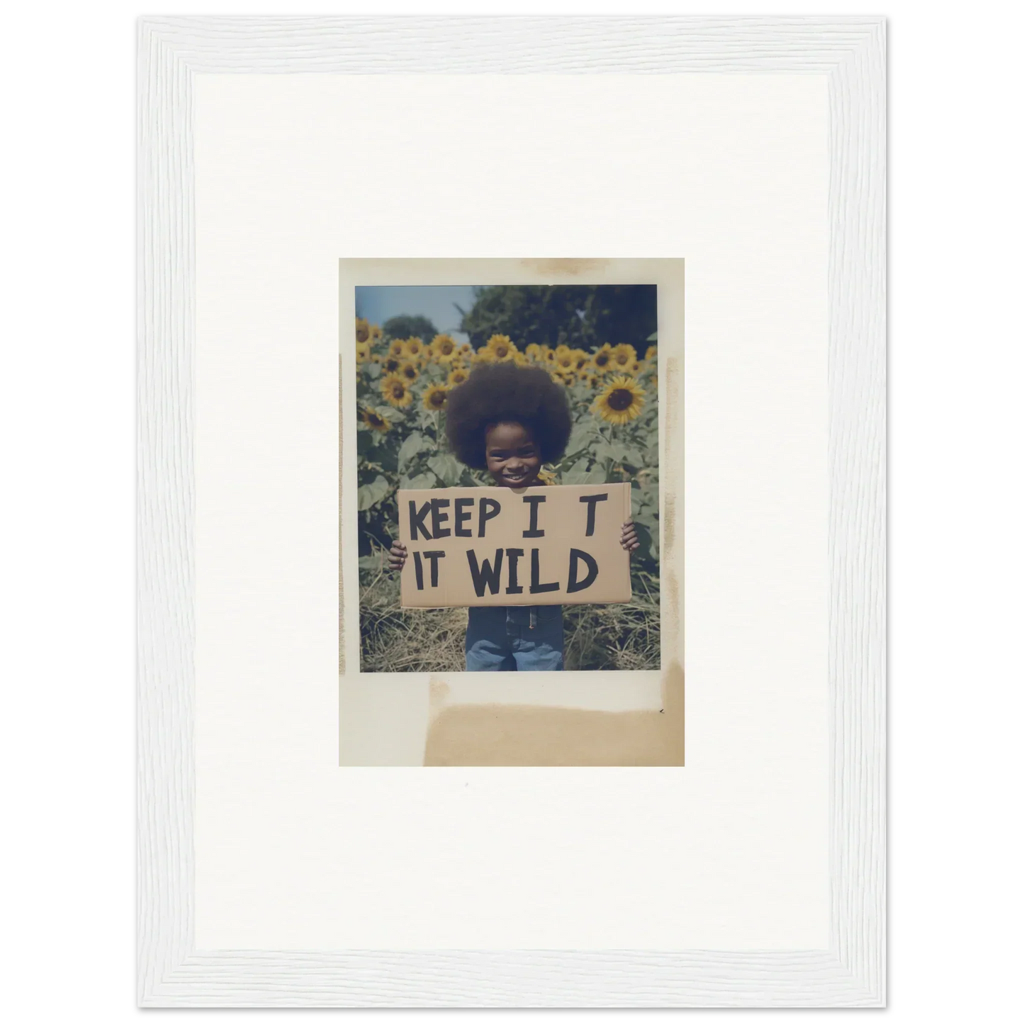 Person holding a KEEP IT WILD sign in a beautiful sunflower wilderness field