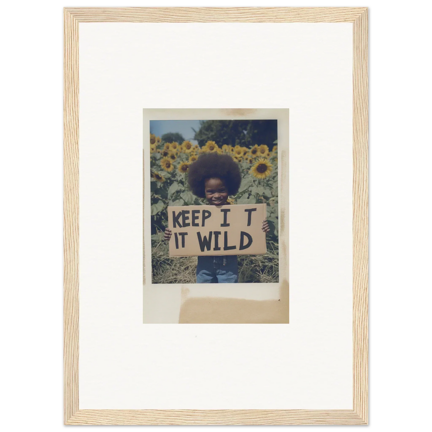 Person holding a KEEP IT WILD sign in a vibrant sunflower wilderness field