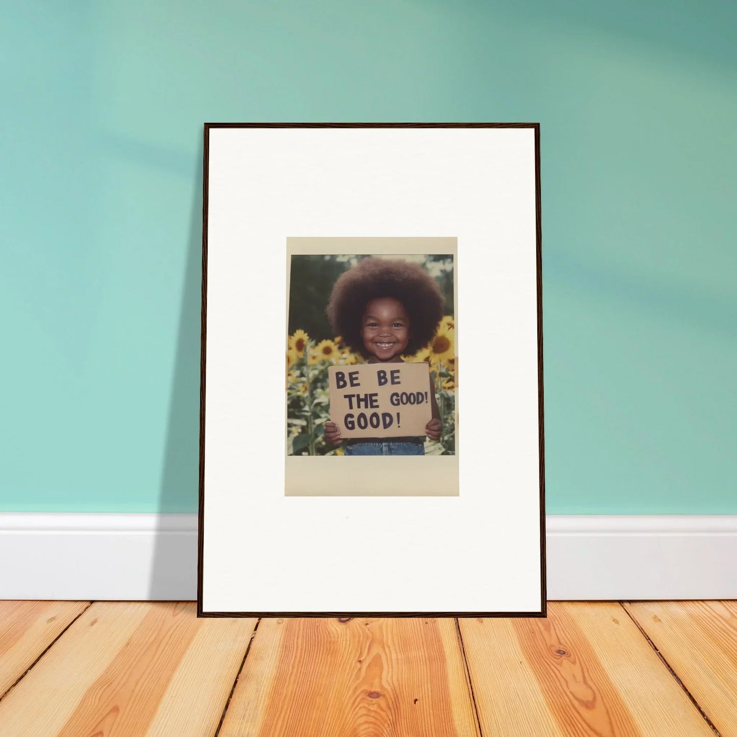 Framed wall art of person holding a BE THE GOOD sign among sunflowers, sunflower’s gentle whisper