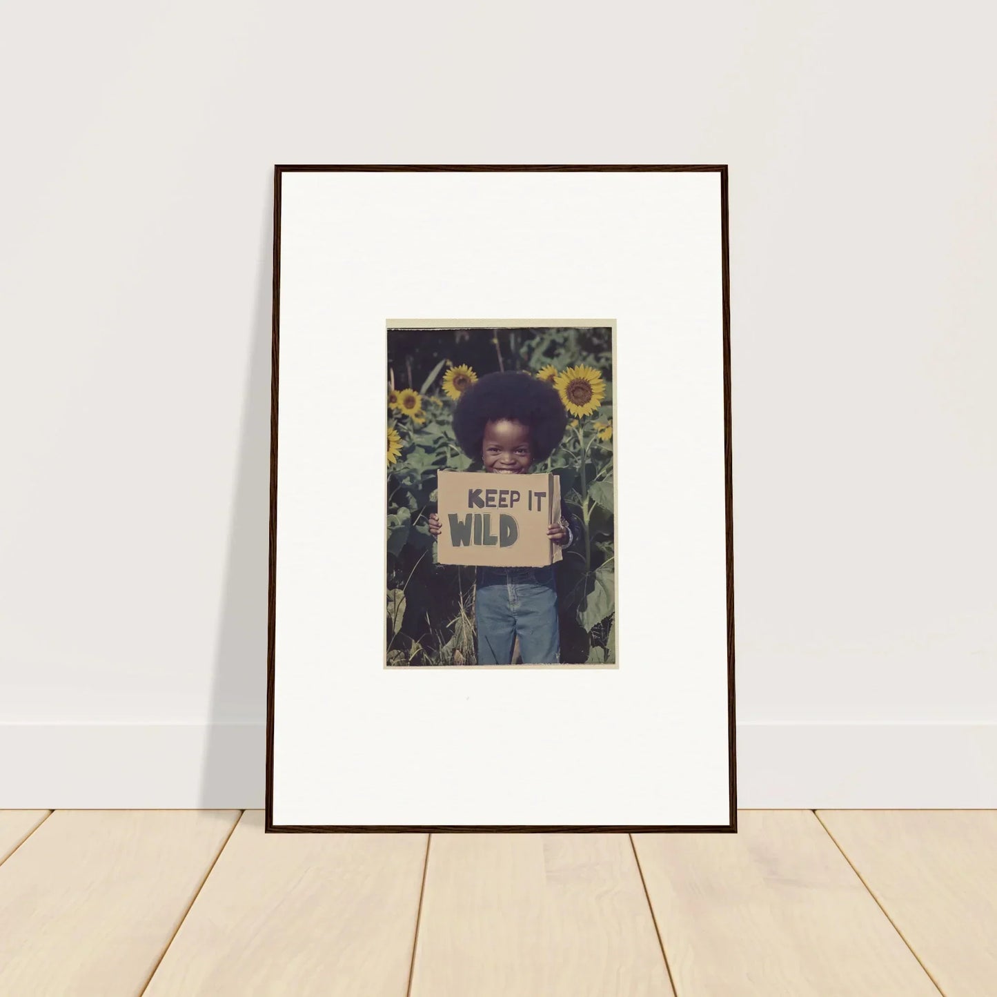 Framed photo of a kid with a Keep it Wild sign in sunflowers for Cosmos Unchained room decoration