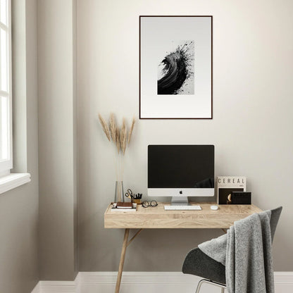 Minimalist home office featuring a wooden desk, computer, and framed wall art decor