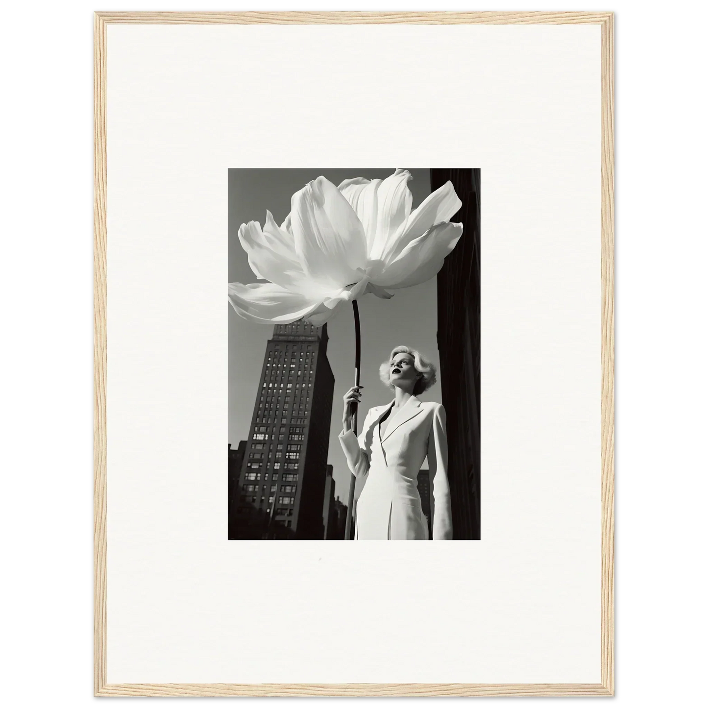 Woman in a white dress holding an oversized flower against an urban backdrop.