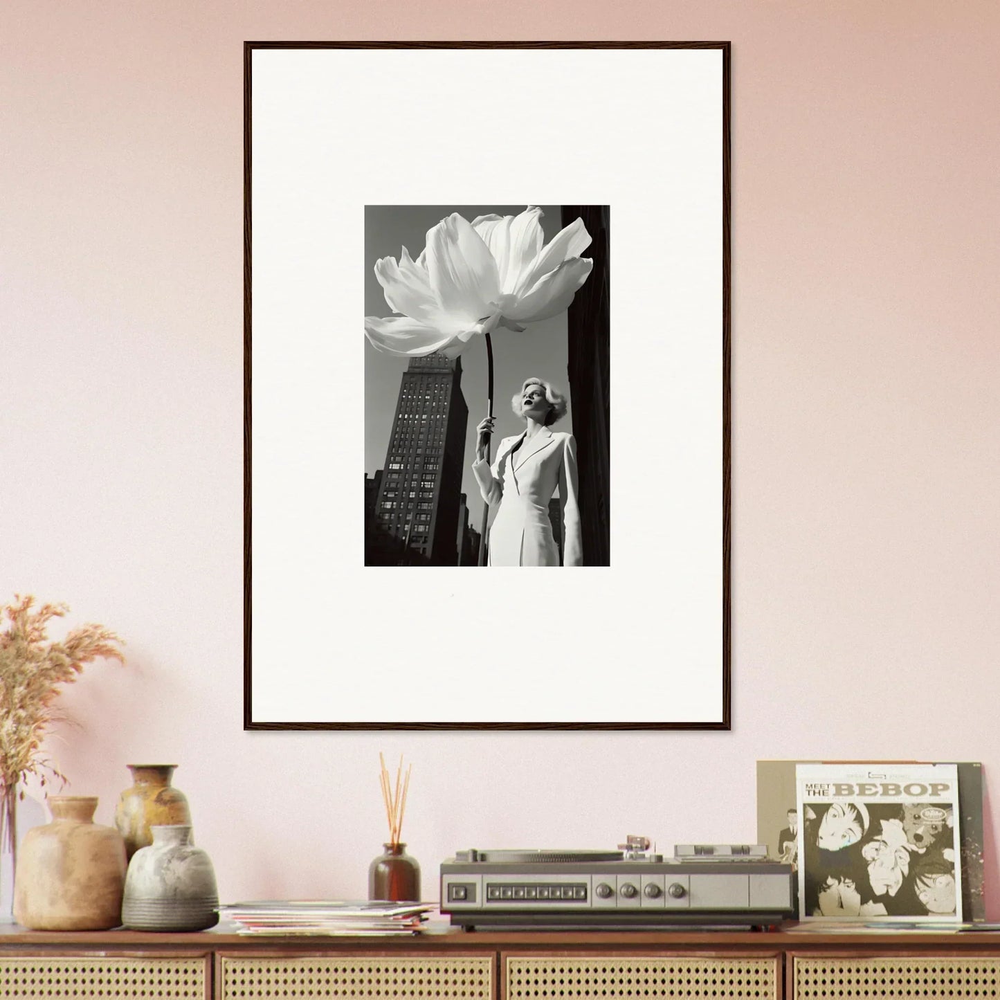 Framed black and white photograph featuring a person and a large flower against a cityscape.