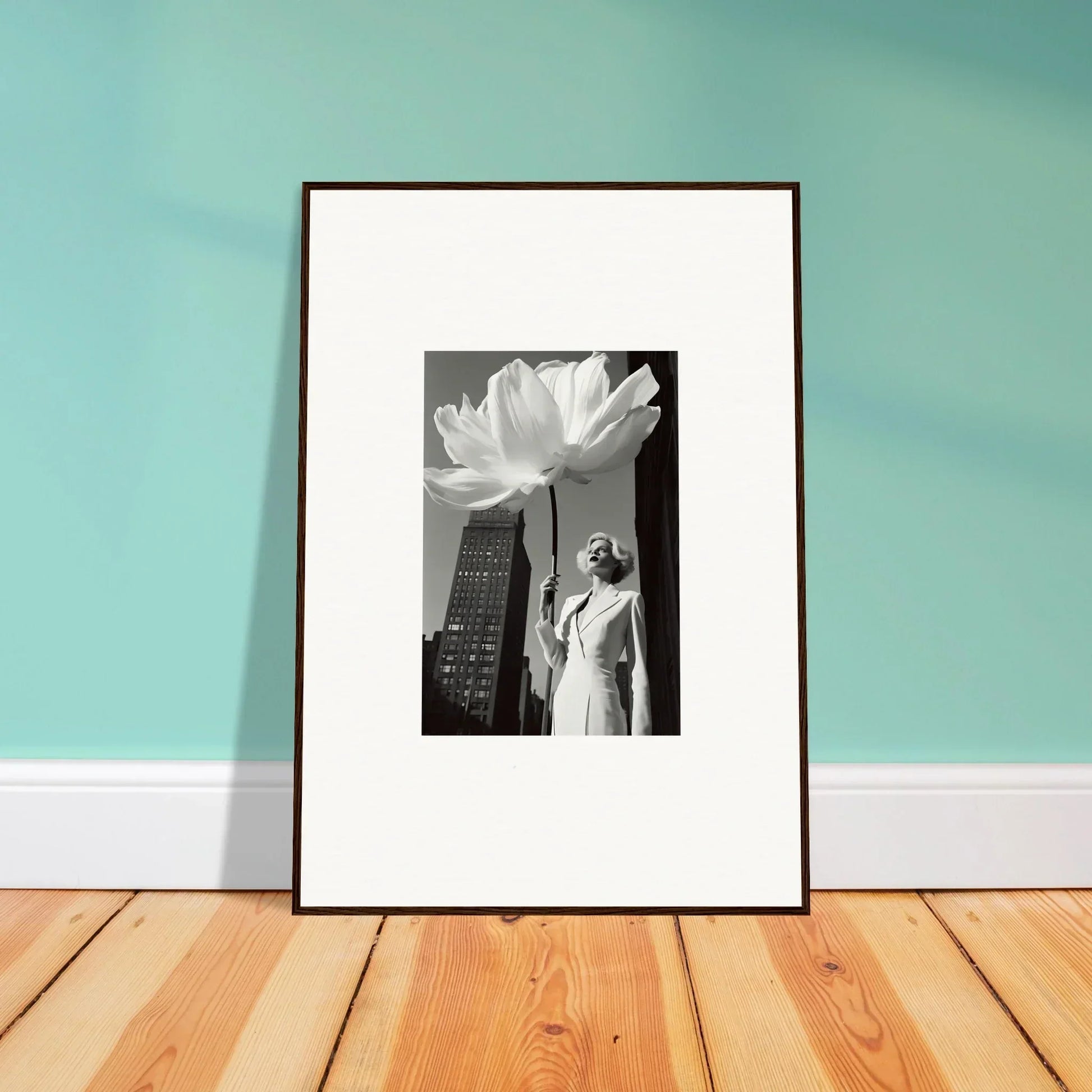 Framed black and white photograph of a person standing beneath a giant flower in an urban setting.