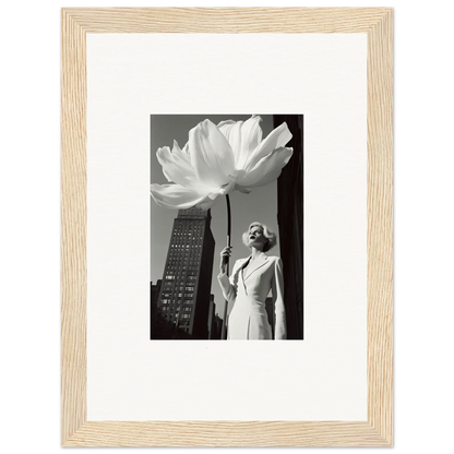 Framed black and white photograph showing a person holding an oversized flower next to a tall building.