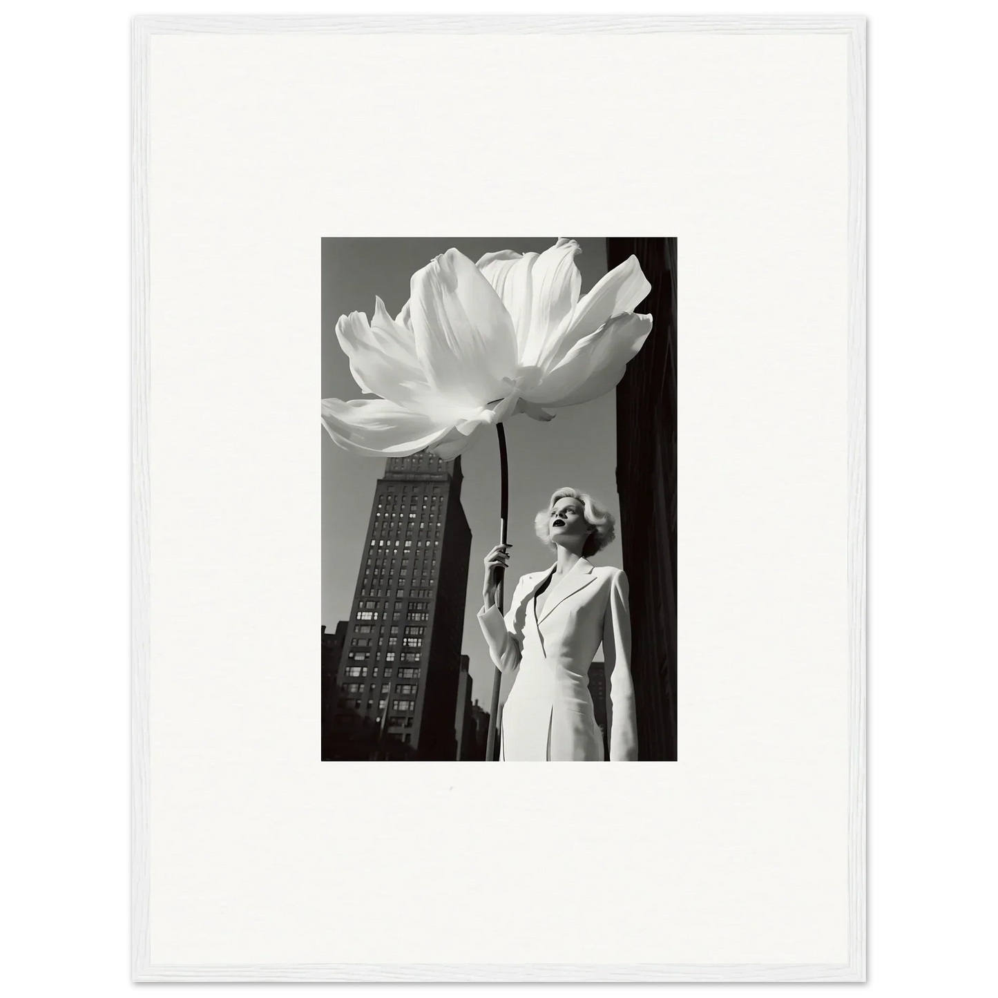 A woman in a white outfit holding an oversized flower against an urban backdrop.