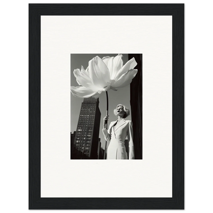 Black and white photograph of a woman standing next to an oversized flower in an urban setting.