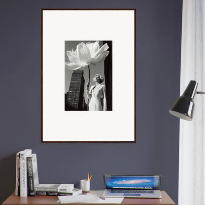 Framed black and white photograph of a person standing next to a giant flower with a city skyline in the background.