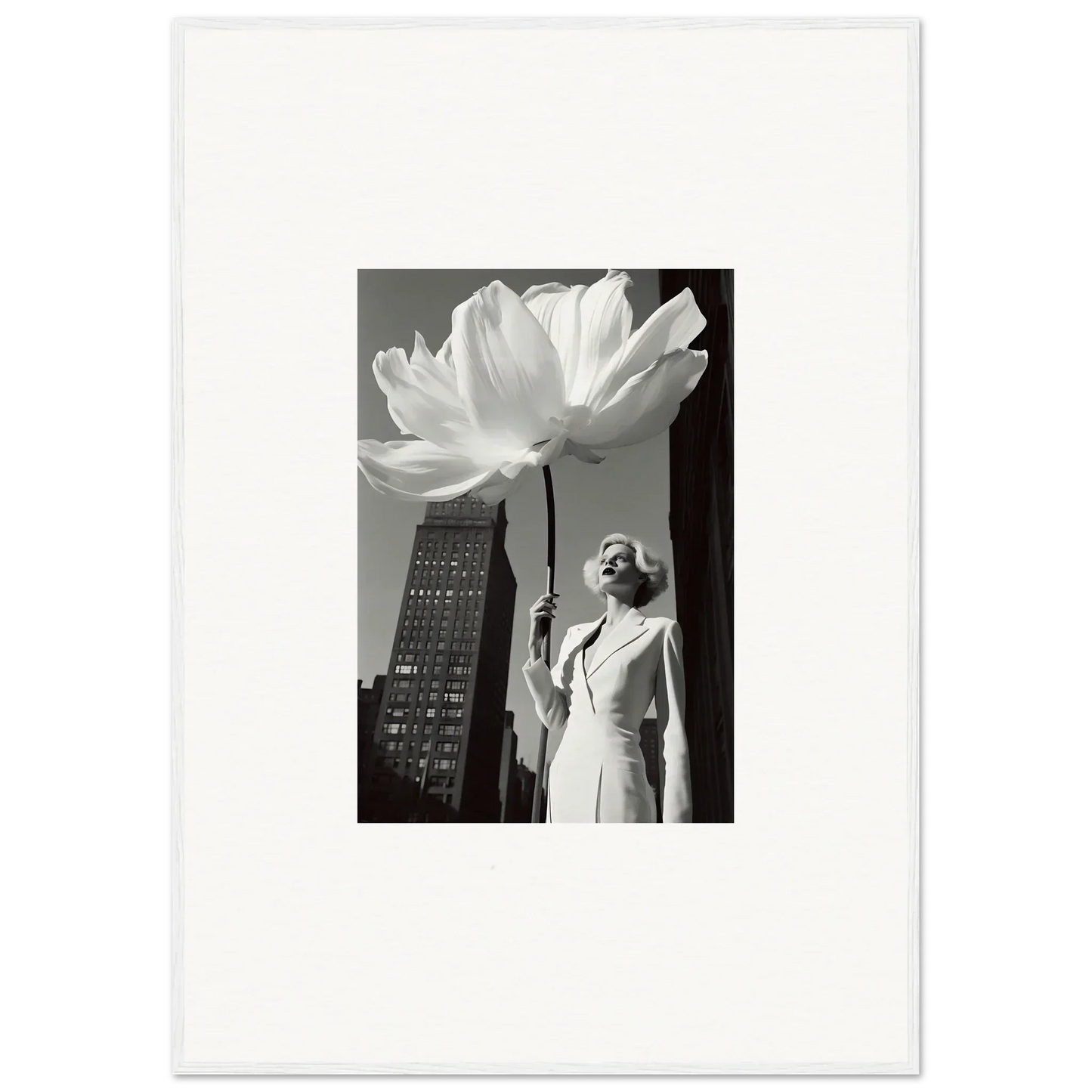 Black and white photograph of a person standing beneath an oversized flower sculpture.