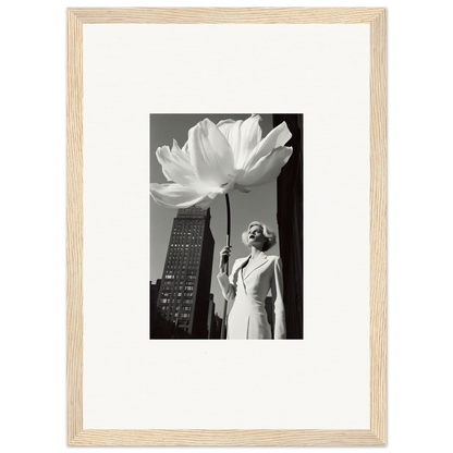 Black and white photograph of a person standing next to an oversized flower sculpture in an urban setting.