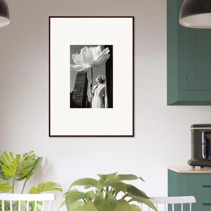 Framed black and white photograph showing a statue and a large flower against a cityscape.