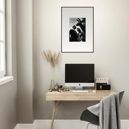 Minimalist home office workspace with a wooden desk, computer, and framed artwork.