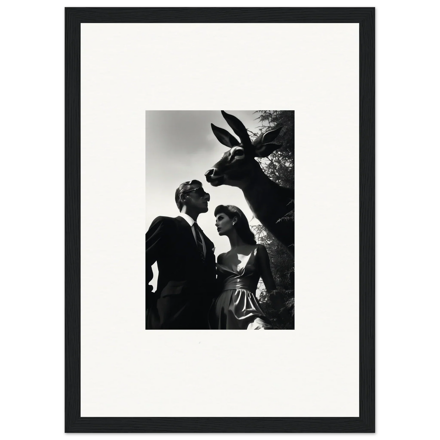 Black and white photograph of a couple with a giraffe peering over them.