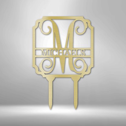 Gold-colored monogram cake topper featuring the letter ’M’ and the name ’MICHAELS’ in an ornate design with scrollwork.