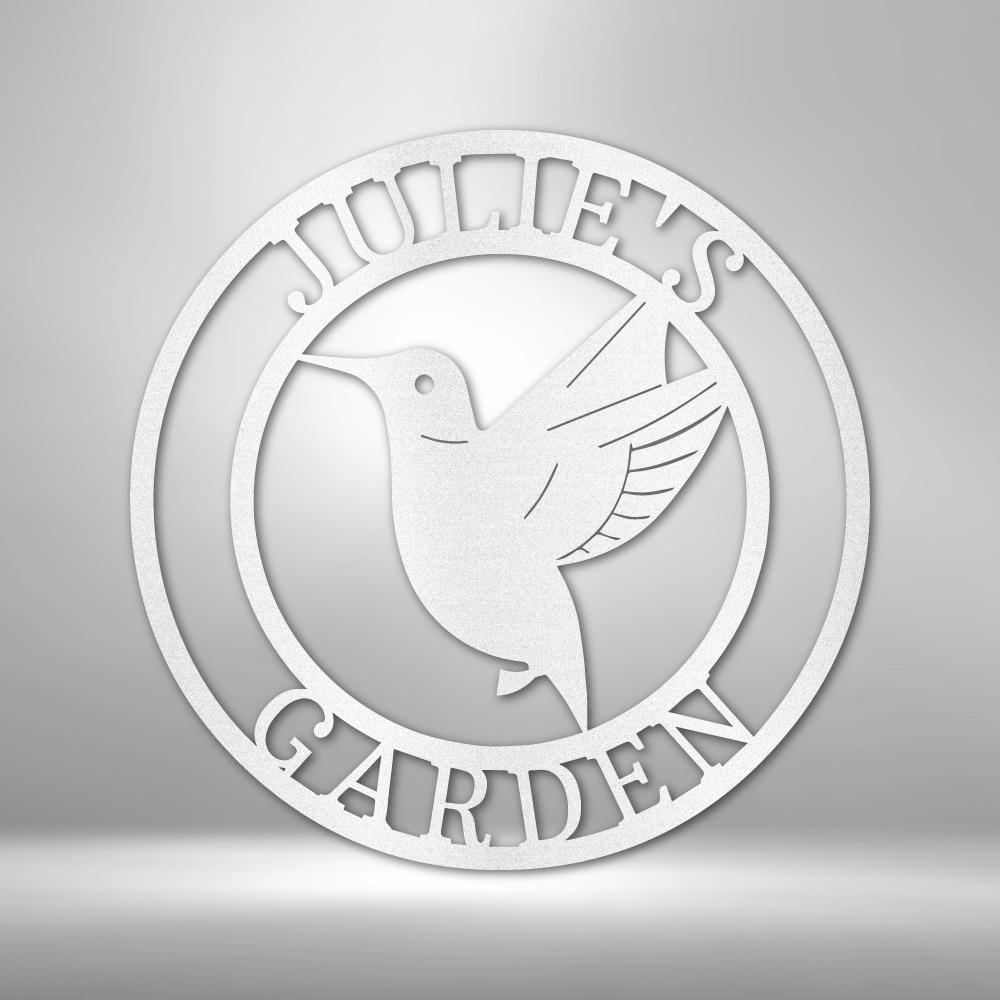 Circular white sign featuring a hummingbird design and the text ’JOHN’S GARDEN’.