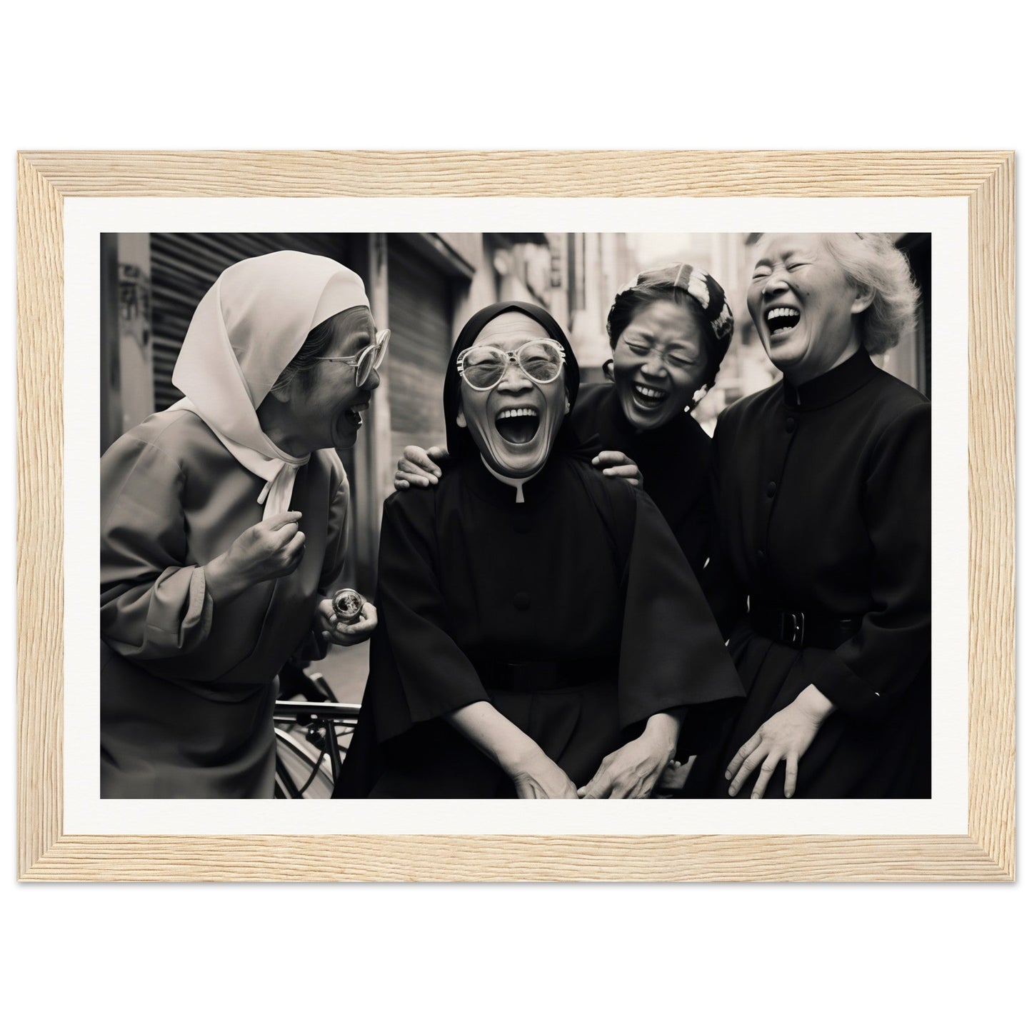 Black and white photograph of four women laughing together, framed in light wood.