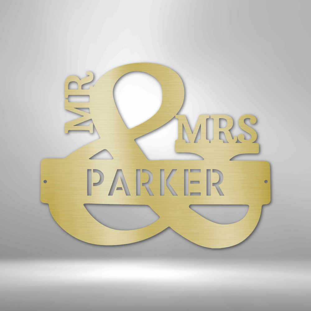 Gold-colored metal sign reading ’MR & MRS PARKER’ with an ampersand as the central design element.