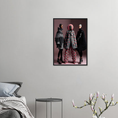 Framed photograph of three people posing in stylish, avant-garde outfits against a dark background.