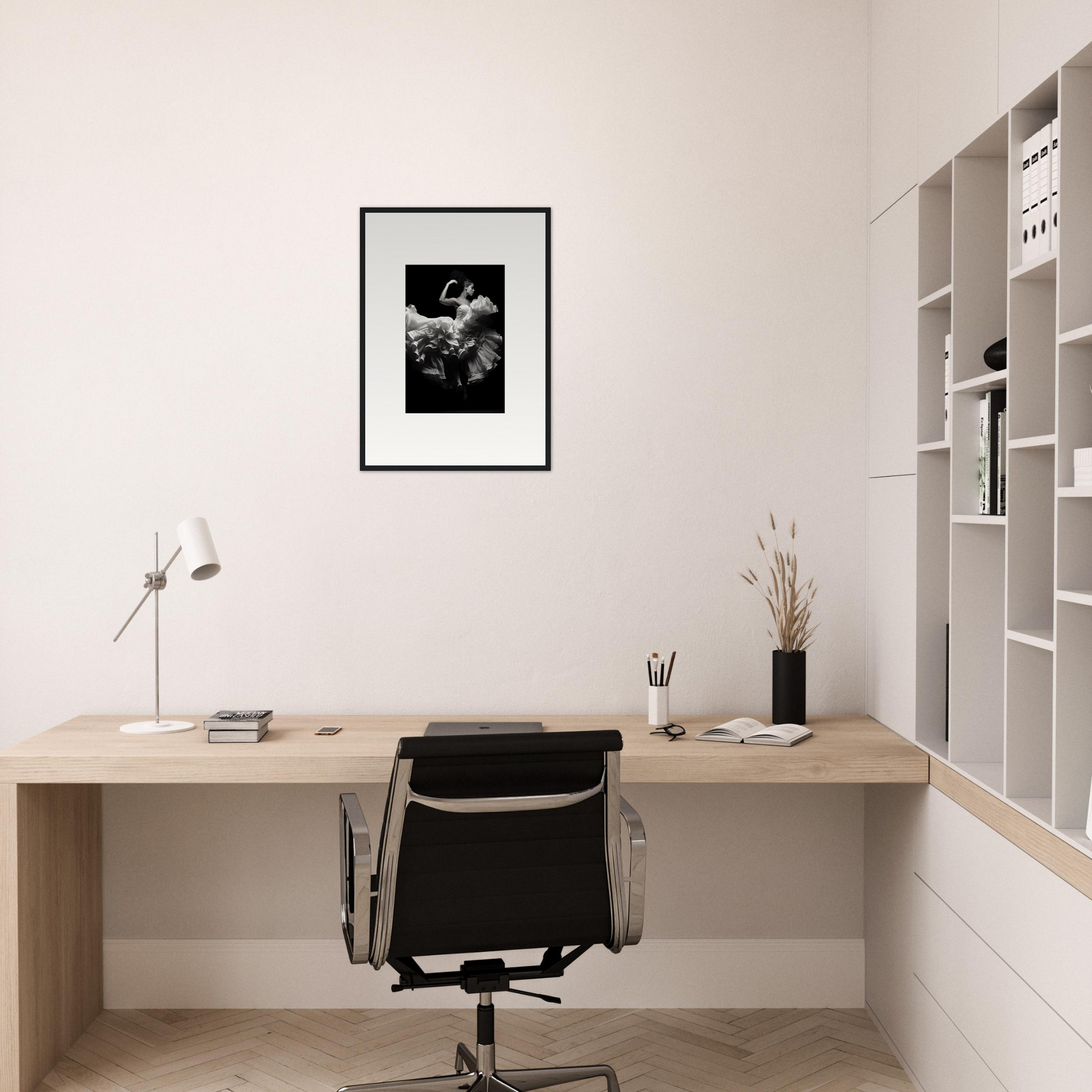 Minimalist home office workspace with a wooden desk, black office chair, and framed artwork on the wall.