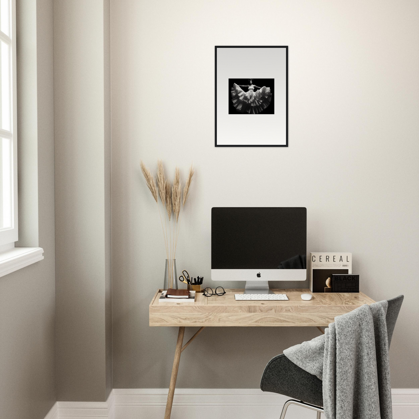 Minimalist home office workspace with a wooden desk, computer monitor, and framed artwork.