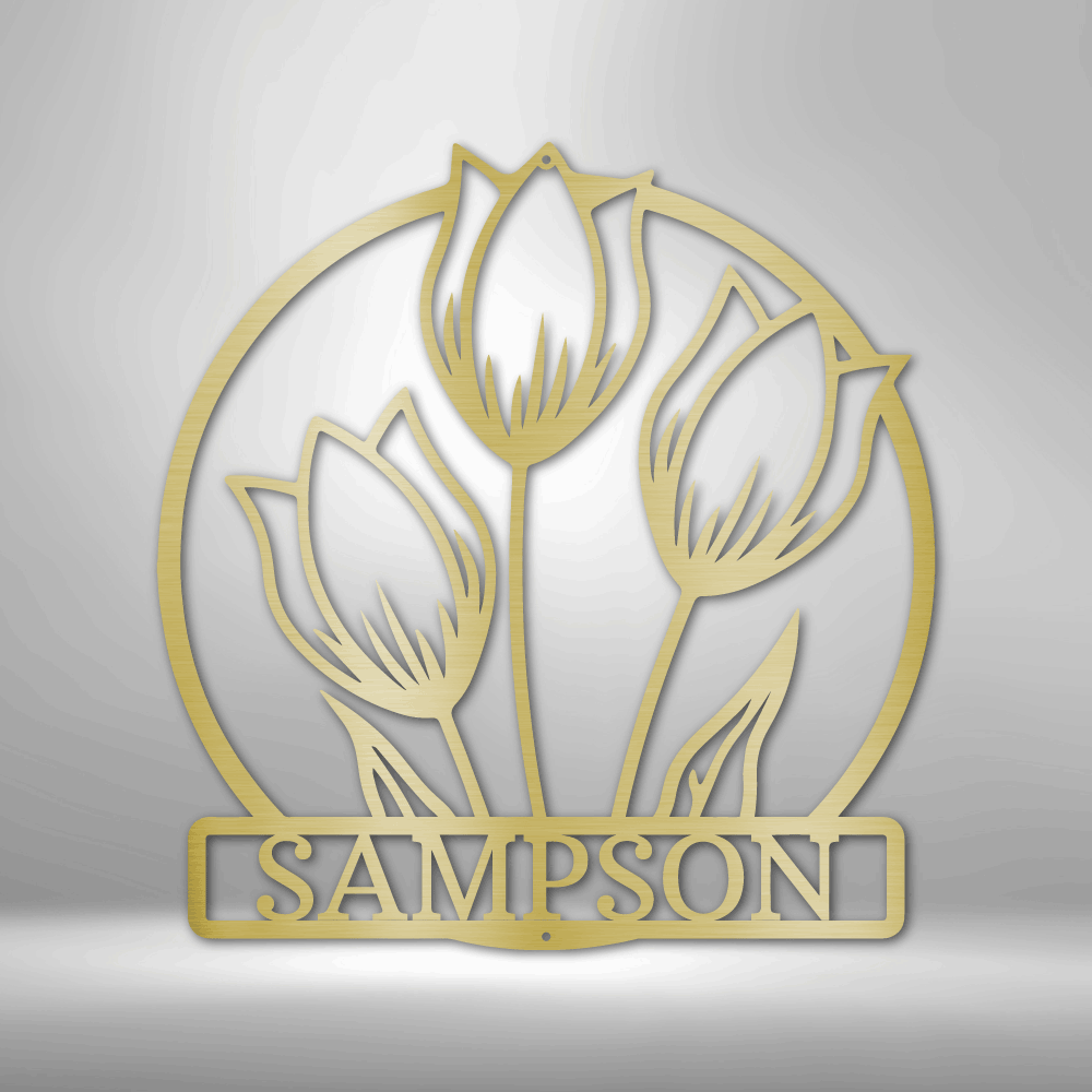 Gold-colored metal wall art featuring three tulips in a circular design with ’SAMPSON’ text below.