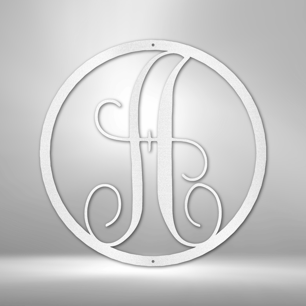 Circular monogram featuring an ornate letter ’A’ in a stylized design.