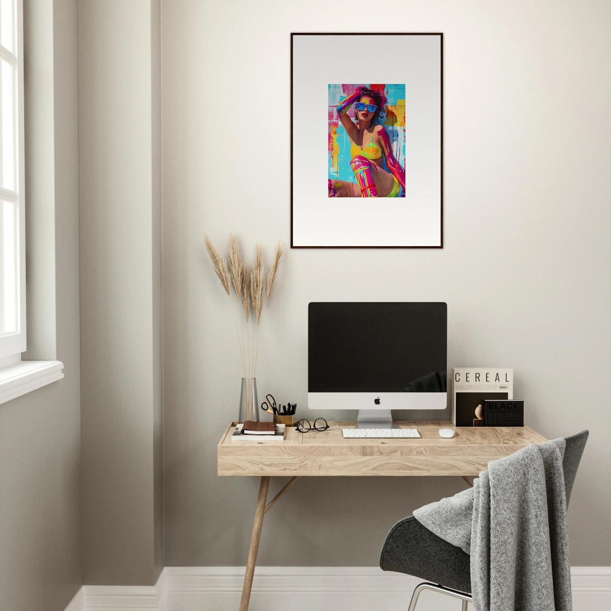 Minimalist home office with a wooden desk, computer, and vibrant wall art decorations