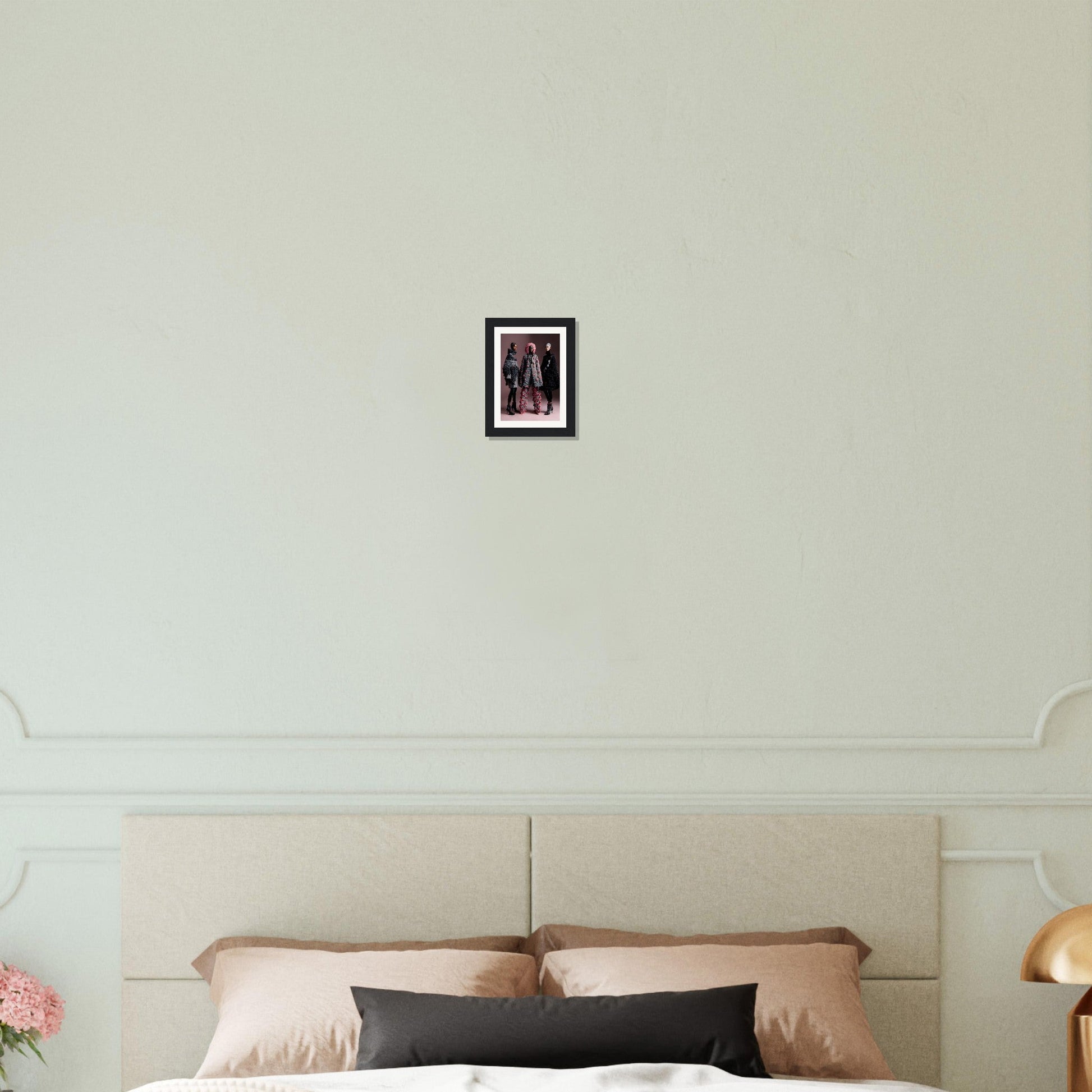 Framed artwork hanging on a white wall above a bed.