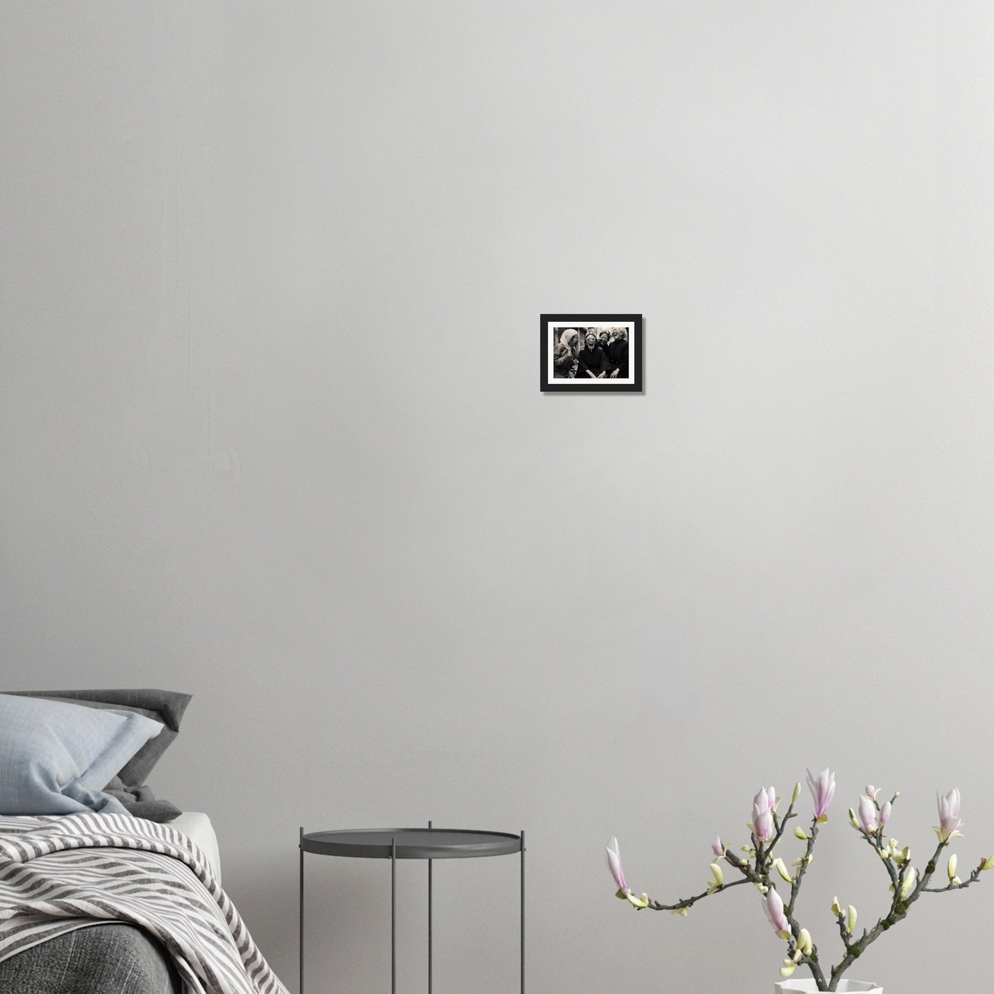 Minimalist bedroom corner with a bed, side table, and flowering plant.